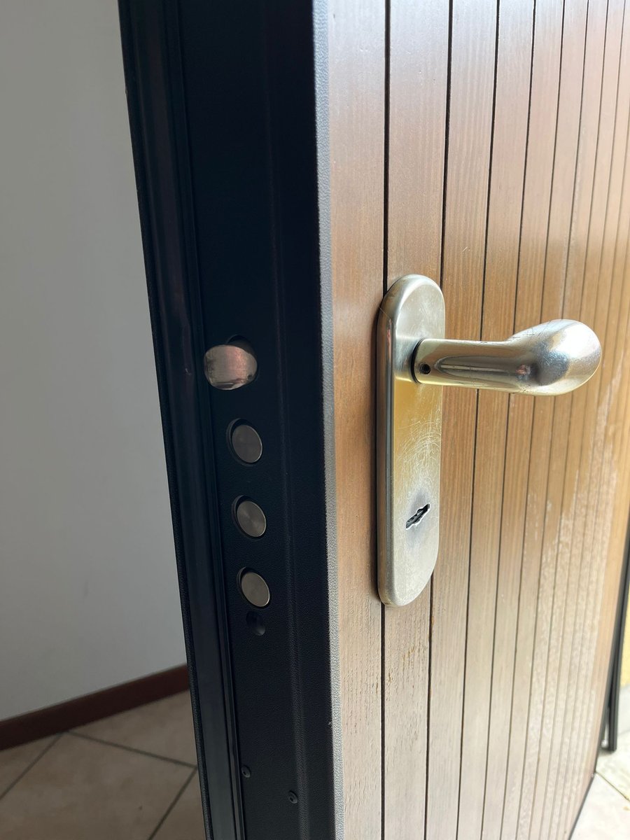 Porta blindata aperta con cremagliera e perni di chiusura visibili durante un intervento